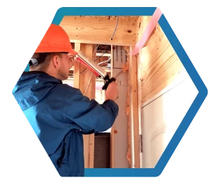 Building performance technician air seals a house under construction