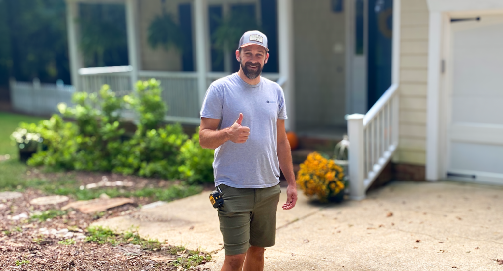 Davison, construction manager at southern energy management, smiles outside of a home on a sunny day with his thumb up after a technical site assessment