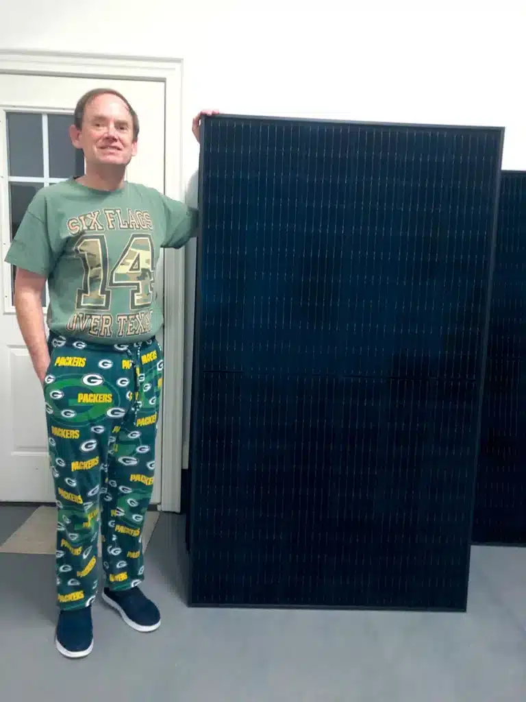 Dennis standing next to a solar panel in his home 