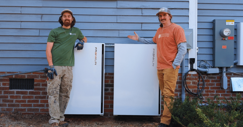 Two solar technicians from Southern Energy stand outside of a home with two FranklinWH apower 2 batteries installed