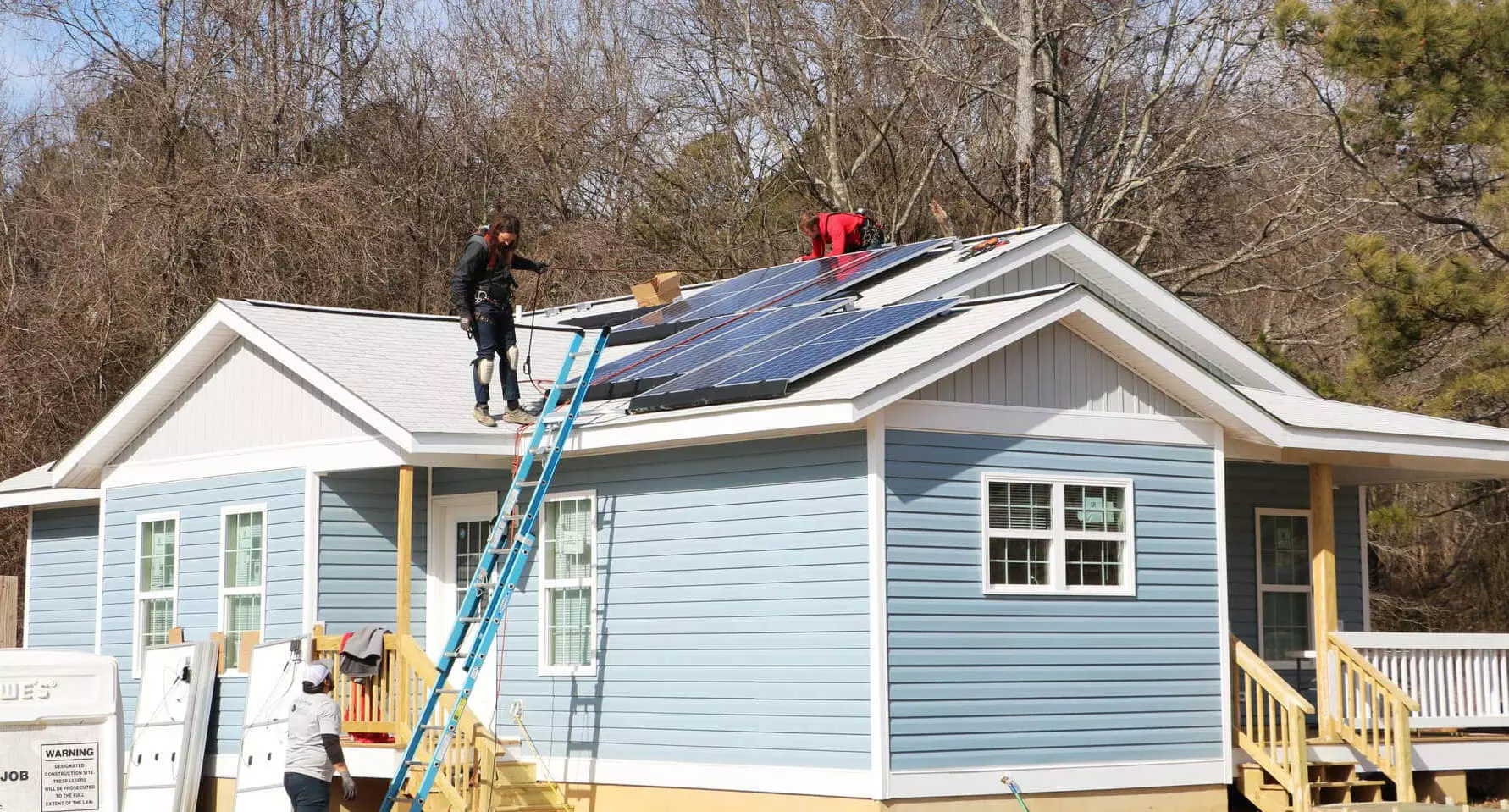 Blue Habitat for Humanity home with solar system installed on the roof
