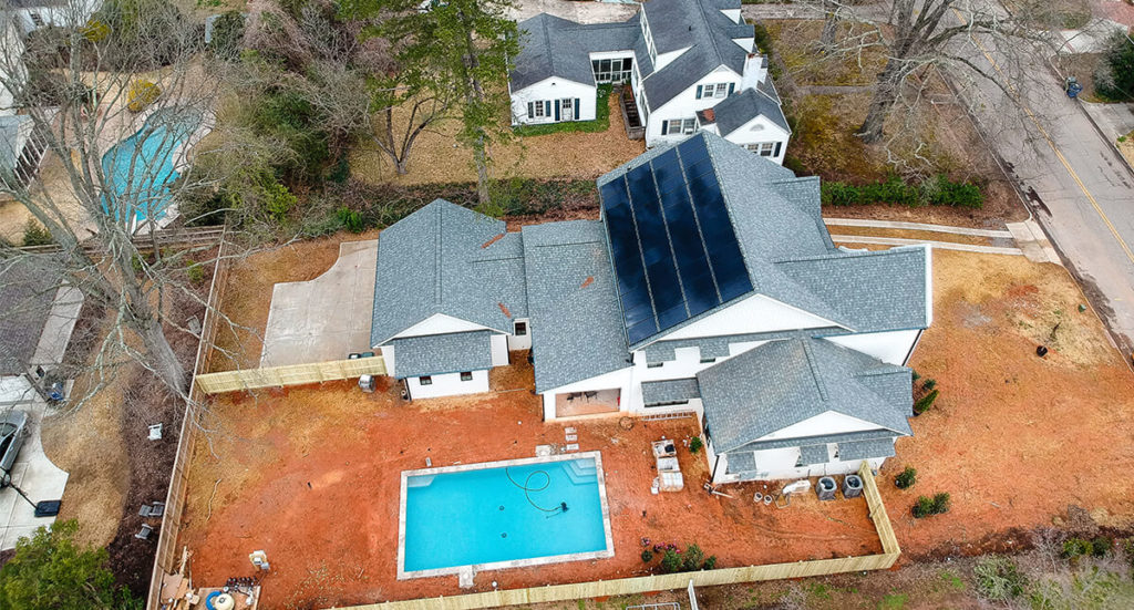 Aerial view of a roof mounted solar system on a new construction home with a pool in north carolina