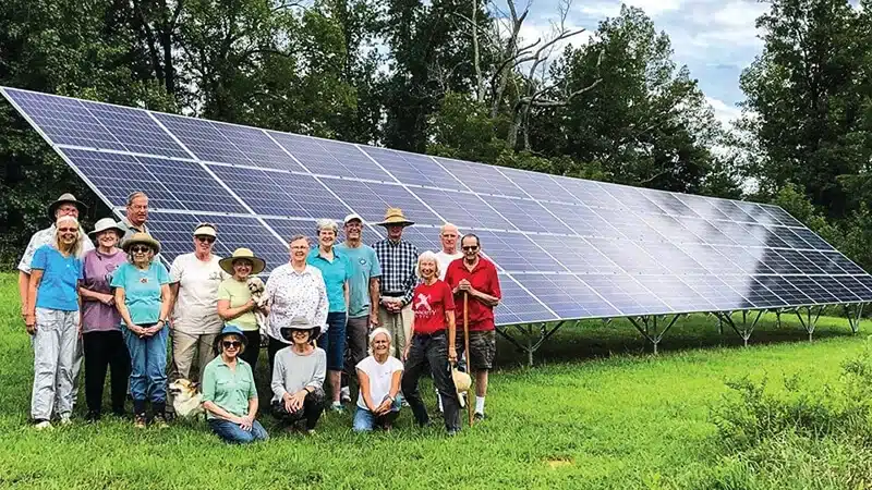 Residents from Elderberry Cohousing standing in front of community ground mount solar system