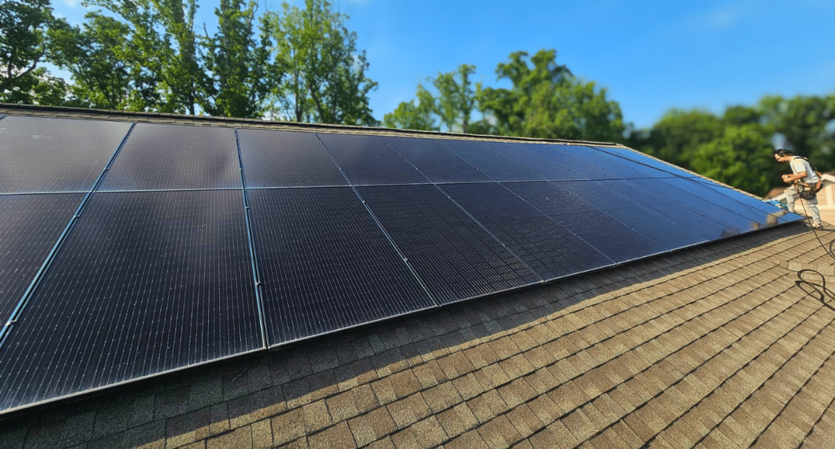 Solar panels being installed on a brown shingled roof in North Carolina