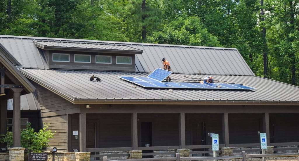 Solar installers from Southern Energy Management on the roof of the visitors center at Umstead State Park laying the solar panels in place