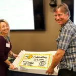 Bob and Maria Kingery, co-founders of Southern Energy Management, holding a cake to celebrate the company's 10 year B Corp anniversary