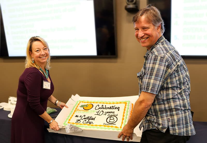 Bob and Maria Kingery, co-founders of Southern Energy Management, holding a cake to celebrate the company's 10 year B Corp anniversary
