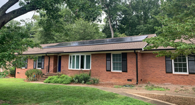 Brick one story home with solar panels on the front roof