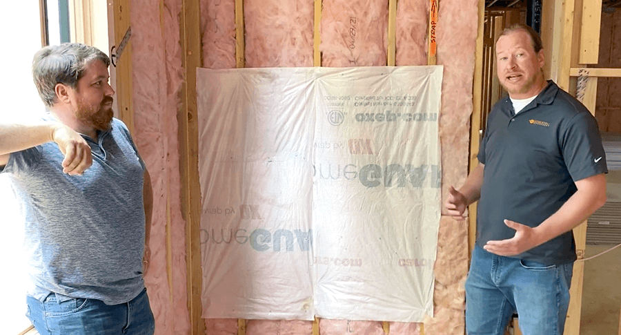Michael and Matt next to a demo wall showing house wrap used as a flexible air barrier