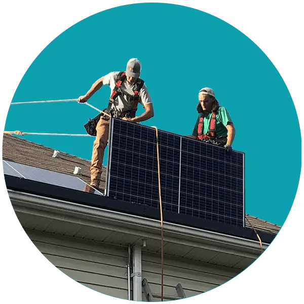 Two installers harnessed on a roof with a solar panel
