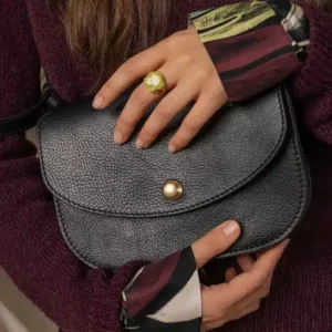 Woman wearing a burgundy sweater holding a black leather saddle bag from Lindquist