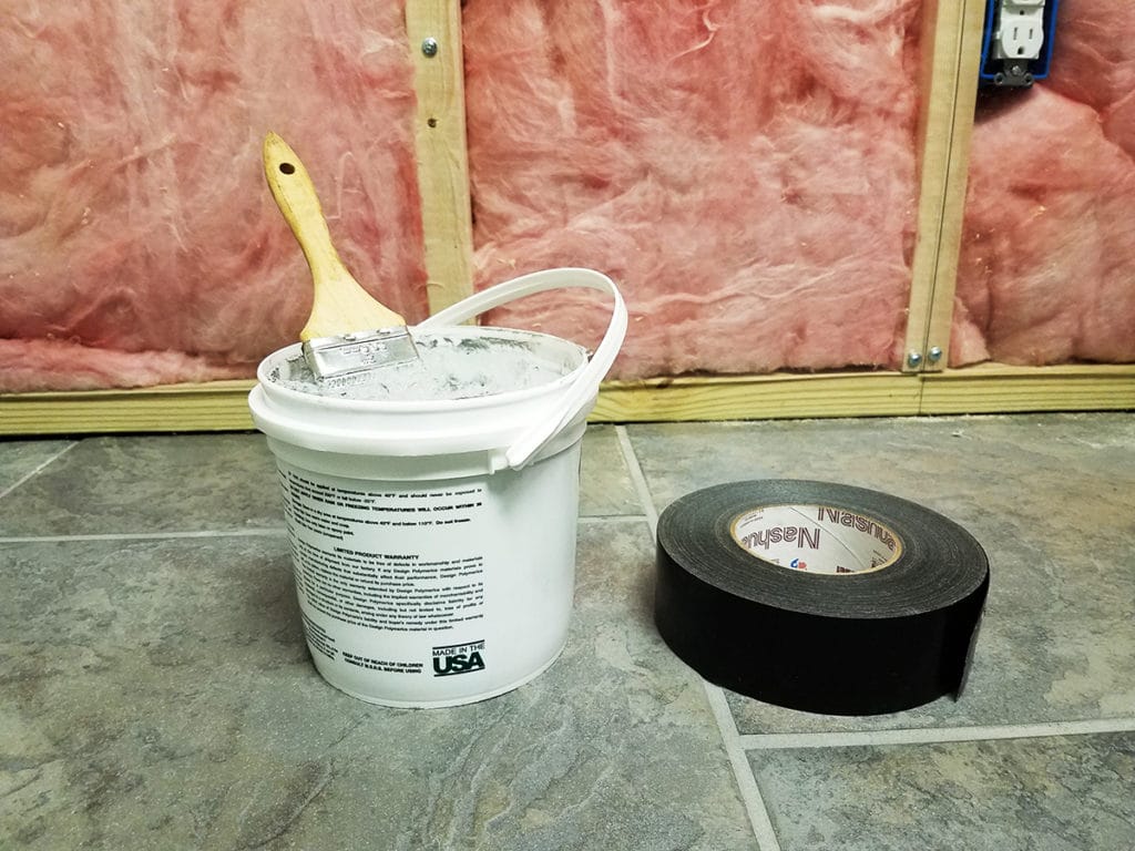 Bucket of mastic next to roll of duct tape