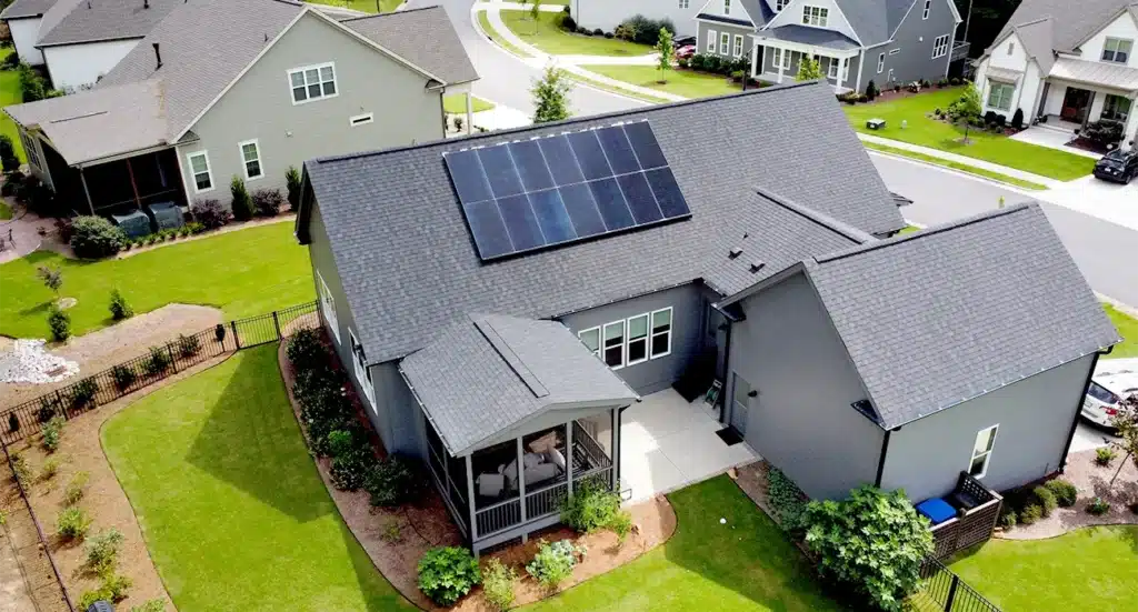 A grey one story new construction home in a Durham, North Carolina Neighborhood with solar panels on the roof
