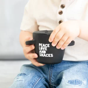 child holding a black snack container that says peace love and snacks from Bella Tunno