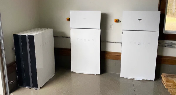 Two tesla powerwall plus systems installed next to a stack of three powerwall2s