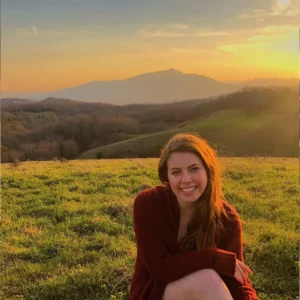Samantha sitting in a scenic field during sunset