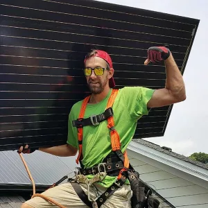 Solar installer carrying a solar panel and showing his strength.