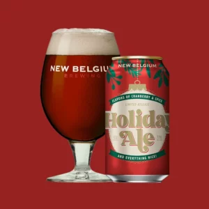 glass of holiday ale in a tulip shaped glass next to the can of holiday ale from New Belgium