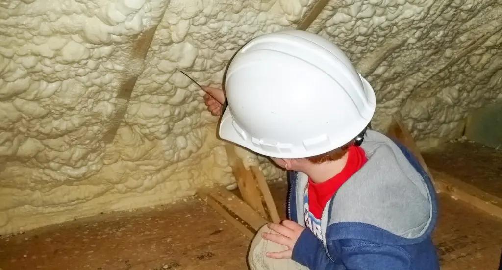 Child inspecting spray foam levels in an attic