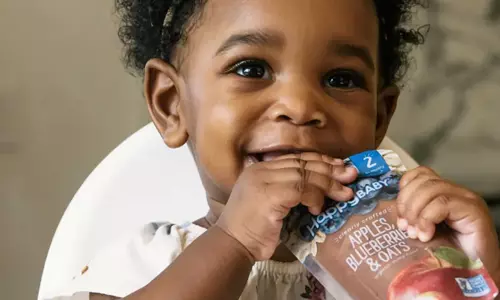 baby eating flavored applesauce in a pouch from Happy Family Organics