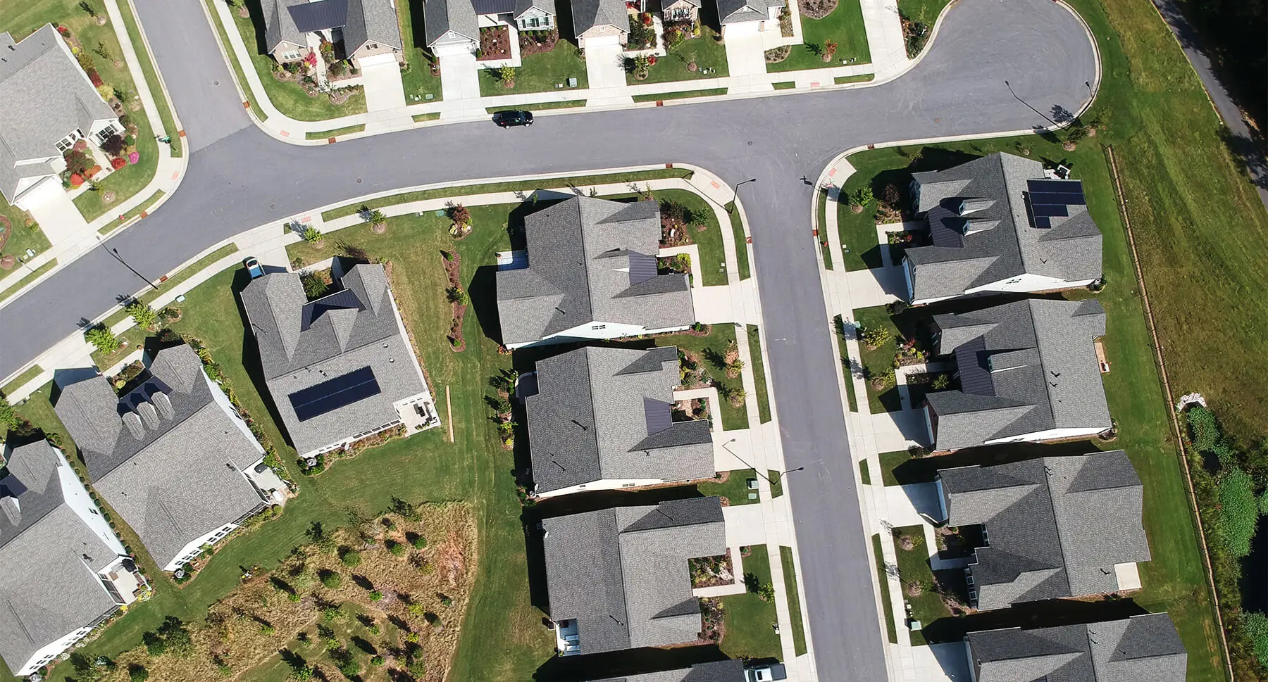 Aerial view of a neighborhood street with two homes that have solar systems