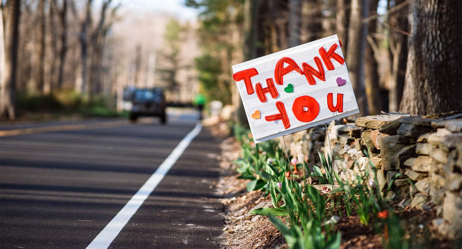 Thank you sign on the side of the road with blooming flowers