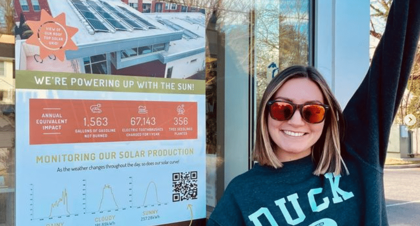 A team member from Walton & Maready Orthodontics poses next to new signage installed outside of the solar powered building